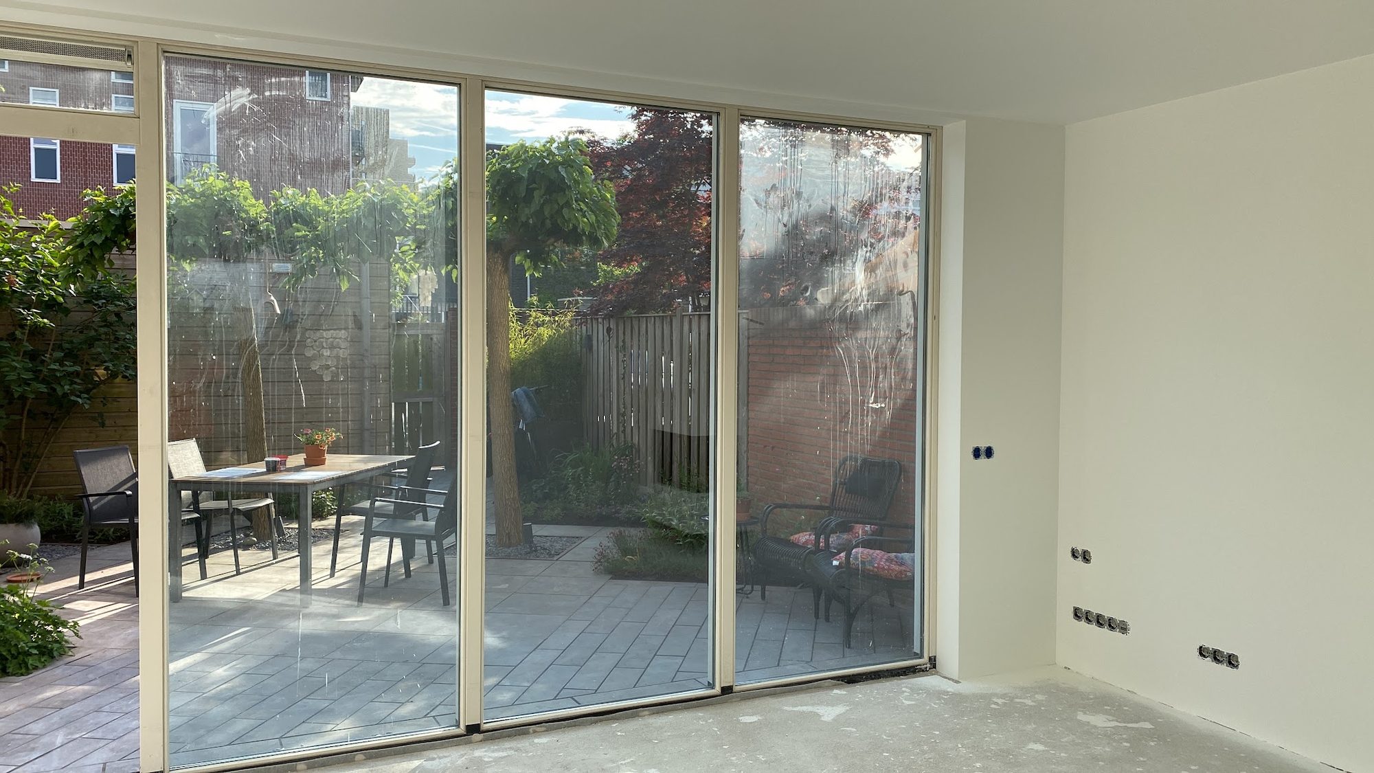 Woonkamer met glazen schuifpui naar de tuin, net gespoten wanden