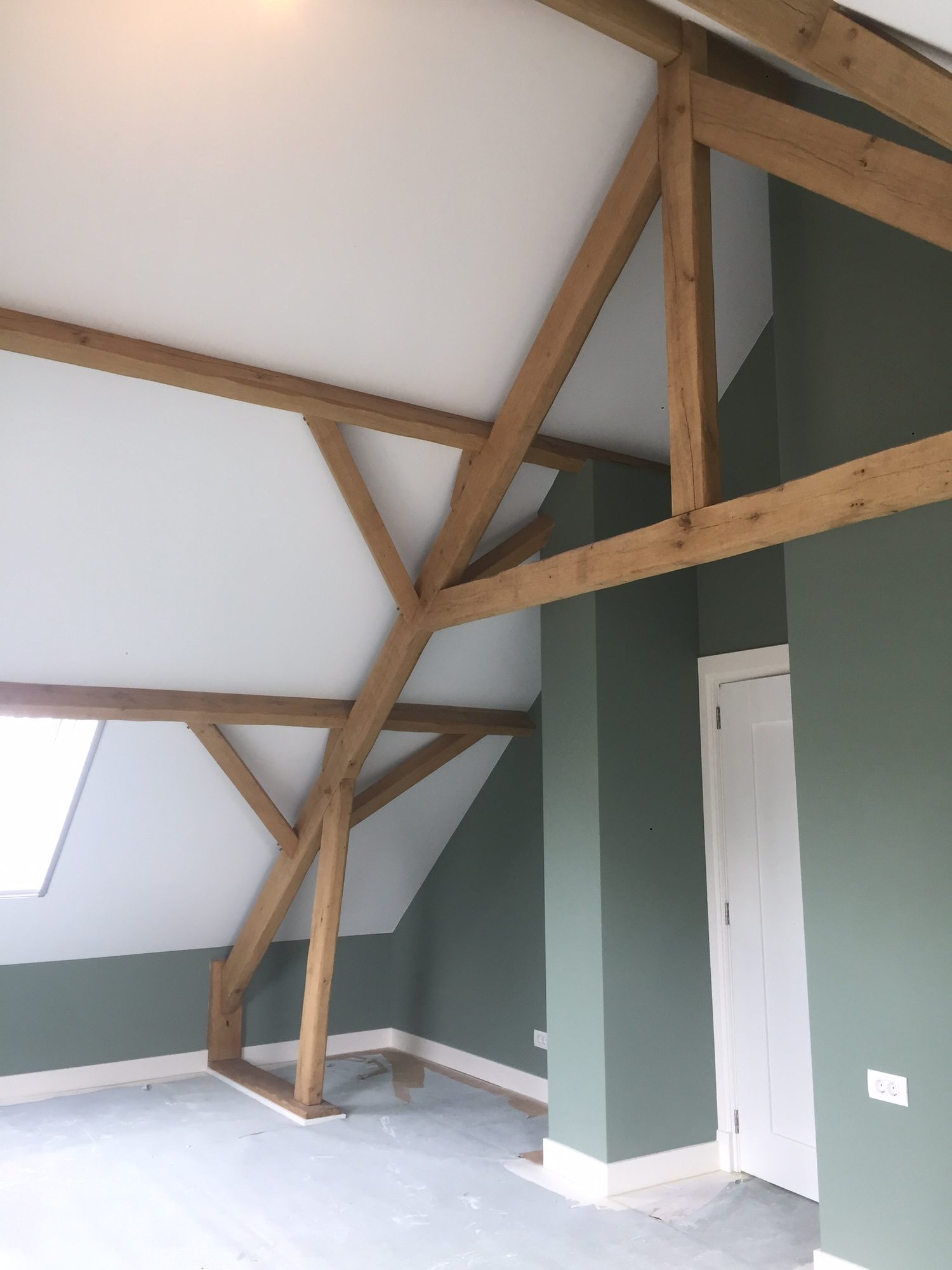 Zolderkamer met houten spanten en saliegroene wanden