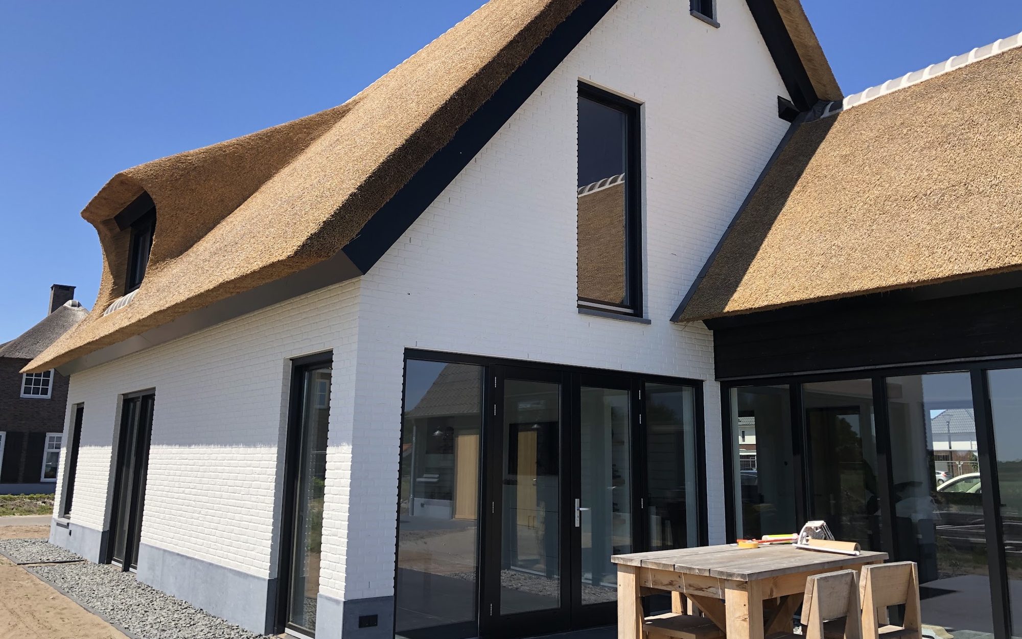 Nieuwbouwwoning met rieten kap, witte gevel en zwarte kozijnen