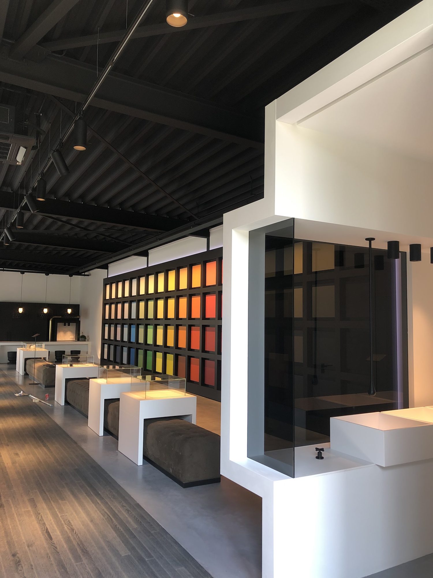 Showroom met een zwart gespoten stalen dak, witte wanden en een wand vol kleurstalen