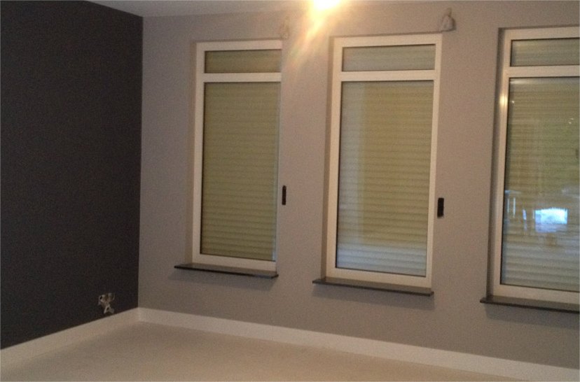 Kamer met een donkere accentwand en drie hoge ramen