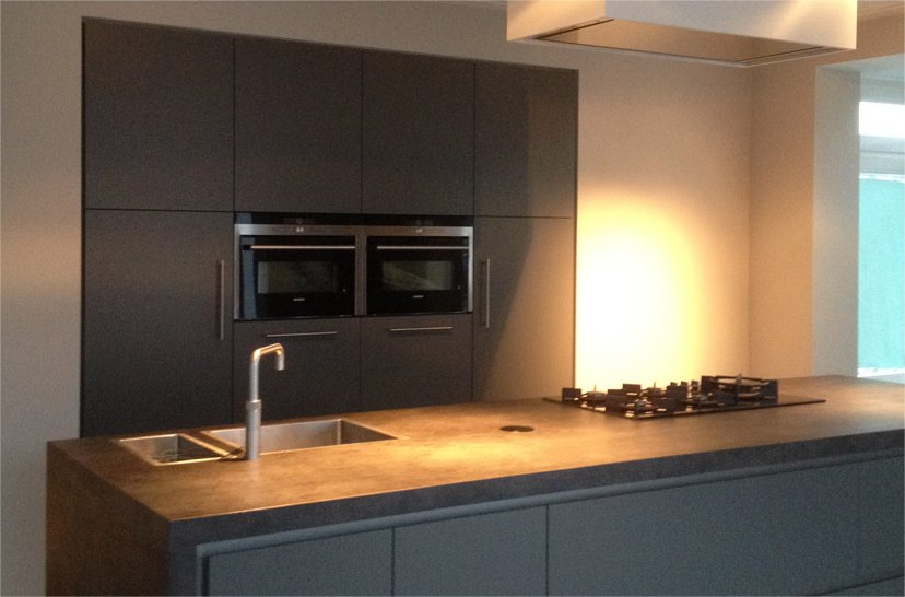 Keuken met donkere kasten en een verlichte wand