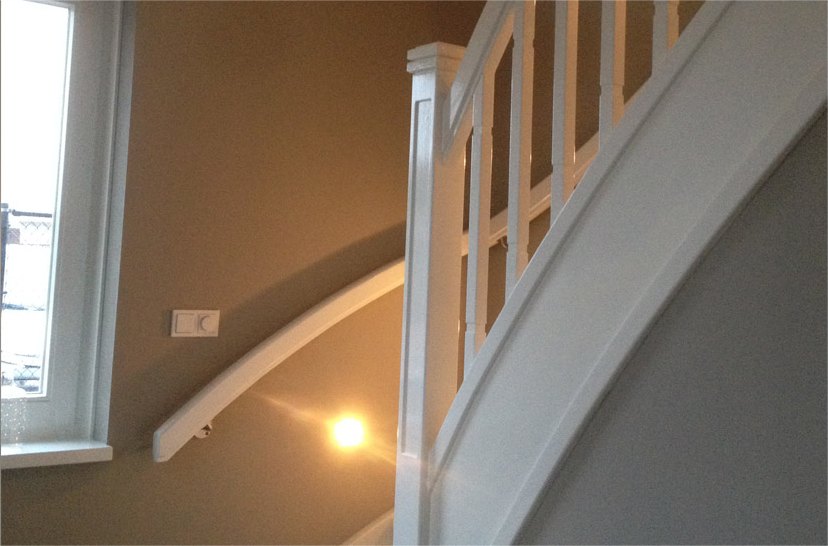 Wit gelakte trap langs een taupe wand