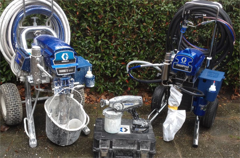 Twee airless-spuitmachines met emmers en een verfblik, buiten tegen een haag